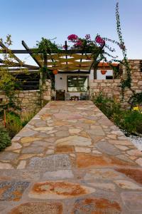 una pasarela de piedra con una pérgola en un patio en Auberge Kalopetri, en Kamiros