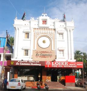 a white building with a clock tower on a street at Le Emerald Residency in Tambaram