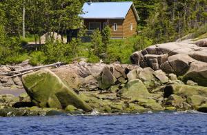 uma cabana de madeira na margem de um rio com pedras em Centre de Vacances 5 Étoiles Family Resort em Sacré-Coeur-Saguenay