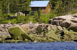 a log cabin on the shore of a river with rocks at Centre de Vacances 5 Étoiles Family Resort in Sacré-Coeur-Saguenay