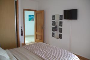 a bedroom with a bed and a television on the wall at Ericeira Sunset Apartment in Ericeira