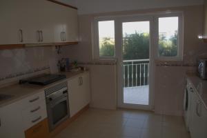 a kitchen with white cabinets and a large window at Ericeira Sunset Apartment in Ericeira