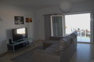 a living room with a couch and a television at Ericeira Sunset Apartment in Ericeira