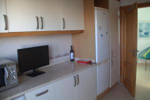 a kitchen with white cabinets and a television on a counter at Ericeira Sunset Apartment in Ericeira
