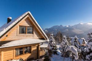 a log cabin in the snow with mountains in the background at udanypobyt Domek Góralski Zakątek in Kościelisko