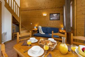 een eetkamer met een tafel en een blauwe bank bij Madame Vacances Lodges des Alpages in La Plagne