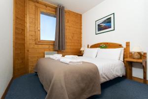 a bedroom with a large bed with towels on it at Madame Vacances Lodges des Alpages in La Plagne