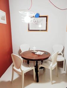 a dining room table with white chairs and a chandelier at Toselli Suite Apartment in Pisa