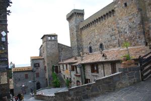 un gran edificio de piedra con dos torres y una calle en La scaletta, en Bolsena