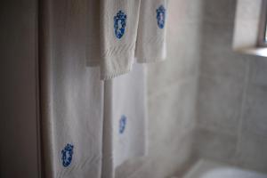 Boutique Hotel Sevilla في لا كومبر: حمام به مناشف بيضاء ذات تصاميم زرقاء على ستارة الحمام