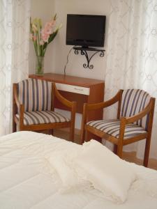 タビアーノにあるAlbergo Elviraのベッドルーム1室(椅子2脚、テレビ、ベッド1台付)