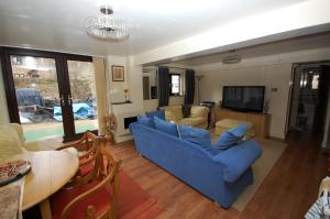 a living room with a blue couch and a tv at 2 bedrooms Bell Cottage in Hoddesdon