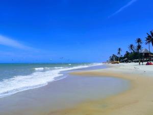 una playa de arena con palmeras y el océano en Kariri Apartaments Sunset Beach, en Cumbuco