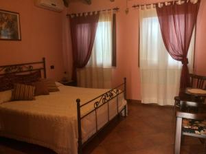 a bedroom with a bed and two windows with curtains at Tenuta Don Ballore in Galtellì