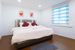 een slaapkamer met een bed met rode kussens en een raam bij Jia Residence in Melaka
