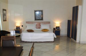 a bedroom with a white bed with two tables and two lamps at Golden Royale Hotel in Enugu