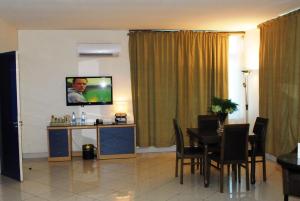 a dining room with a table and a television on a wall at Golden Royale Hotel in Enugu