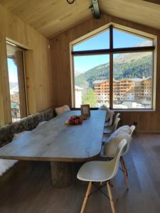 a large wooden table in a room with a large window at Le Chalet des Boisses, Luxury Ski-In Ski-Out Chalet for 12 in Tignes