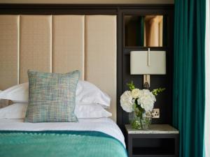 um quarto com uma cama e um vaso de flores sobre uma mesa em Grand Central Hotel Belfast em Belfast