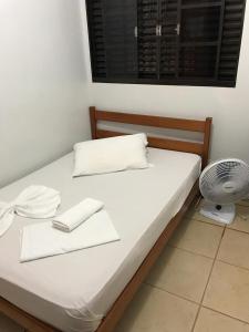 Una cama con sábanas blancas y un ventilador en una habitación. en Hotel Nacional en Jataí