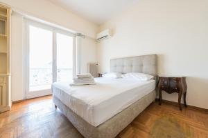 - une chambre avec un grand lit et une grande fenêtre dans l'établissement Victoria Capitan Apartments, à Athènes