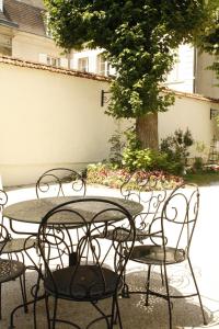 a group of tables and chairs with a tree at LA MONGEARDIERE in Ay