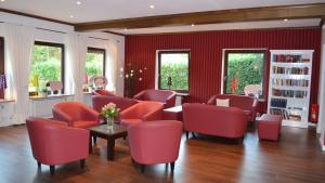 a living room with red chairs and bookshelves at Heide´s Hotel Pension Bad Bevensen in Bad Bevensen