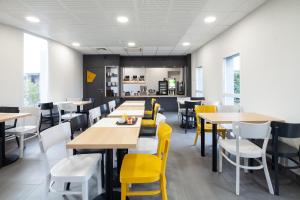 un comedor con mesas y sillas amarillas en B&B HOTEL Saint-Witz, en Saint-Witz