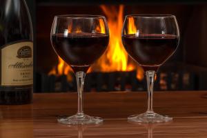 two glasses of red wine on a table with a fireplace at Casa de la Panadería in Los Navalucillos