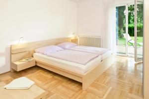 a white bedroom with a bed and a window at Apartments Hauskaernten in Velden am Wörthersee