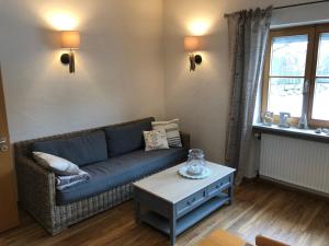 a living room with a blue couch and a table at Chiemsee Beachhouse Apartment in Bernau am Chiemsee