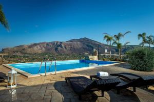 a swimming pool with chairs and a mountain in the background at Villa Thalia in Castellammare del Golfo