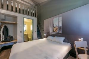 a bedroom with a large white bed and a chair at B&B HOTEL Orgeval in Orgeval