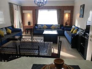 Marina Apartment Agadir في أغادير: غرفة معيشة مع أريكة زرقاء وطاولة