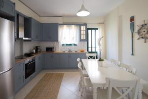 eine Küche mit blauen Schränken und einem weißen Tisch mit Stühlen in der Unterkunft KHouses Maissonette in Lefkada Town