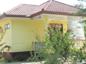 uma pequena casa amarela com um telhado vermelho em Kalinka Inn em Gili Meno