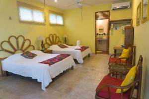 una camera d'albergo con tre letti e una cucina di Sea Hawk Suites a Isla Mujeres