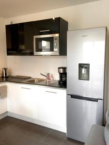 a kitchen with white cabinets and a stainless steel refrigerator at Appartement Copenhague Disneyland in Montévrain