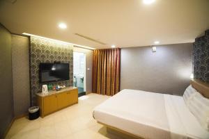 1 dormitorio con 1 cama y TV de pantalla plana en Love Hotel, en Pingtung City