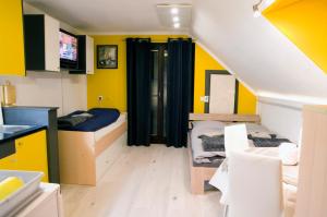 a room with two beds and a kitchen with yellow walls at Apartma LINA, Encijan D-38 in Bohinj