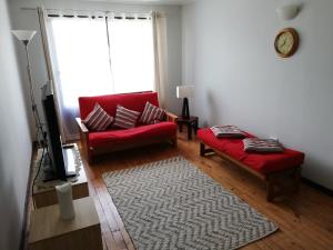 una sala de estar con 2 sofás rojos y una alfombra en Departamento acogedor en centro de San Fernando, en San Fernando