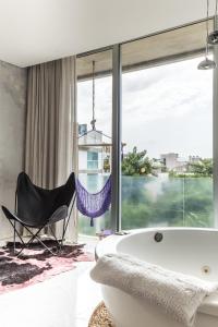 a bathroom with a tub and a chair next to a window at Be Playa in Playa del Carmen
