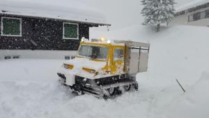 a yellow bulldozer in the snow in front of a house at Alpenchalet Garfrescha in Sankt Gallenkirch