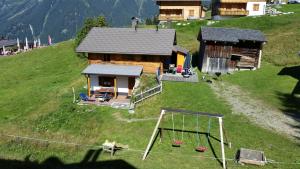 a small house on a hill with a playground at Alpenchalet Garfrescha in Sankt Gallenkirch
