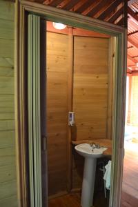 ein Badezimmer mit einem Waschbecken und einer Holzwand in der Unterkunft Chalet Y Cabinas Hibiscus in Cahuita