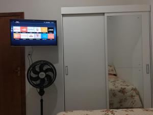 阿雷格里港的住宿－Próximo à ACISP, APM, PUC e UFRGS，卧室配有风扇和墙上的电视。