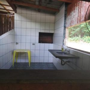 a bathroom with a sink and a yellow stool at Camping Monte Hermom in Ubatuba