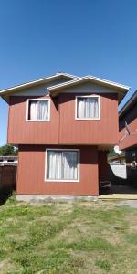 una casa marrón con ventanas blancas en el lateral. en Cabañas Jael, en Licán Ray