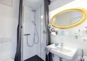 a bathroom with a shower and a sink and a mirror at Apart Hotel Fulda in Fulda
