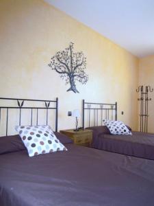 1 dormitorio con 2 camas y un árbol en la pared en CASA RURAL LOS POCICOS, en San Carlos del Valle